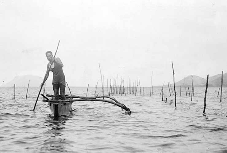 historical black and white photo of hawaiian man in a one-man pontoon fishing boat