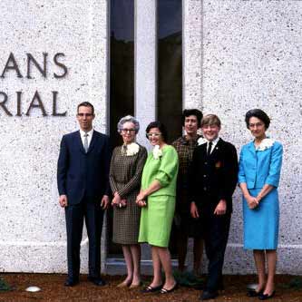 Six people standing in front of a building, on which the words "Veterans Memorial" are partly visible